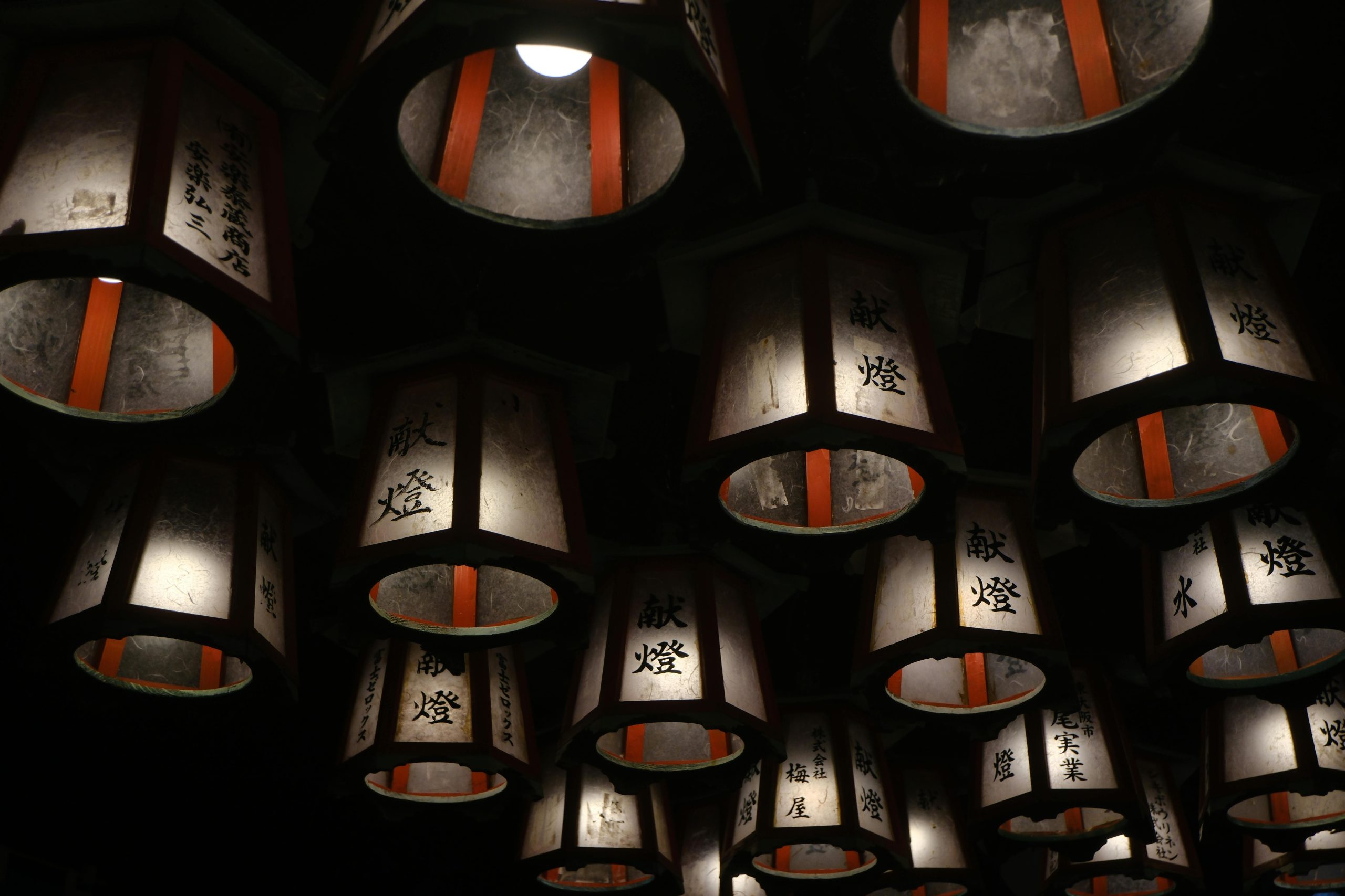 Illuminated traditional Japanese lanterns hanging in the dark, offering a serene ambiance in Shirahama.