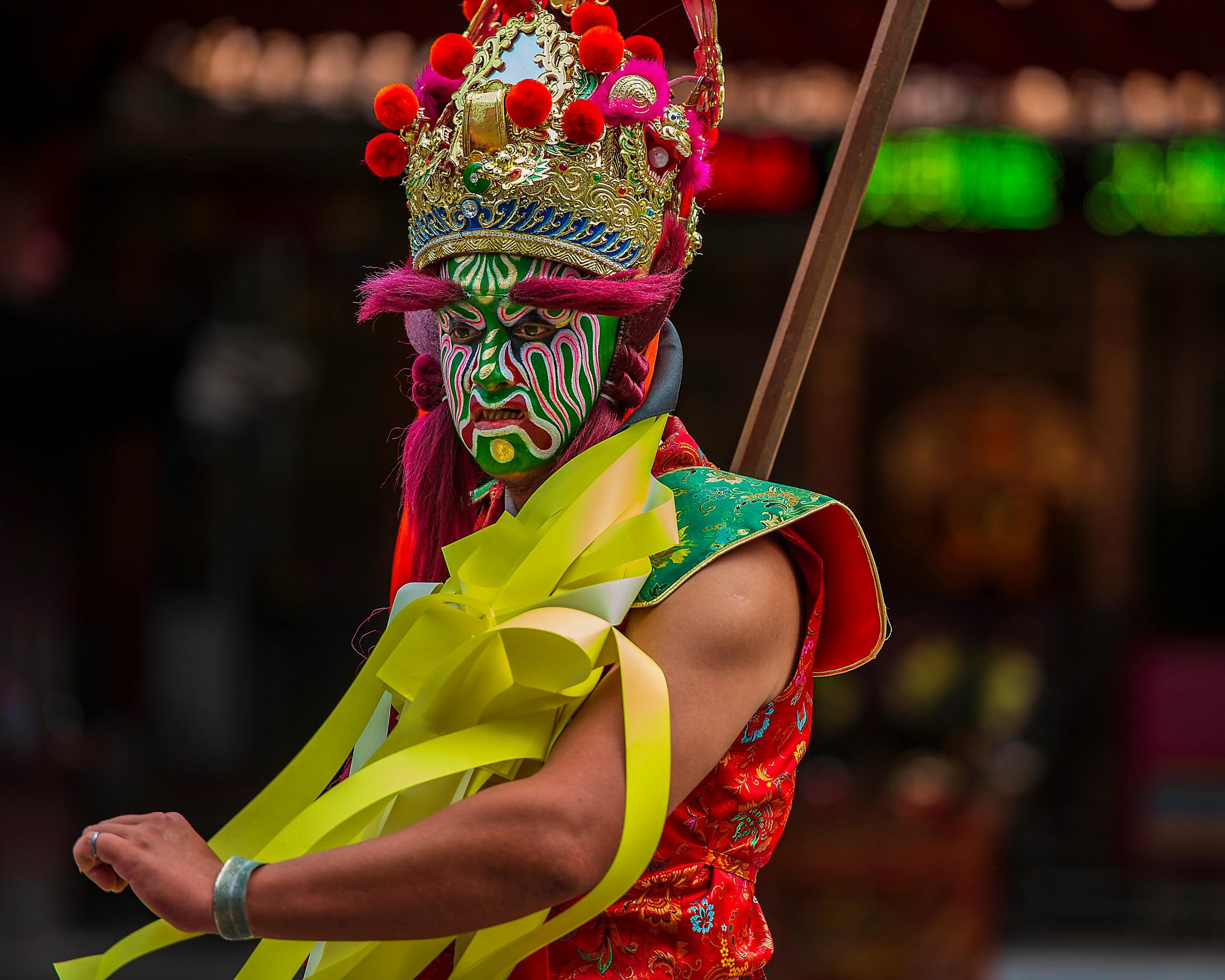 A vibrant cultural performer with intricate face paint and costume captured during a festival in Taiwan.