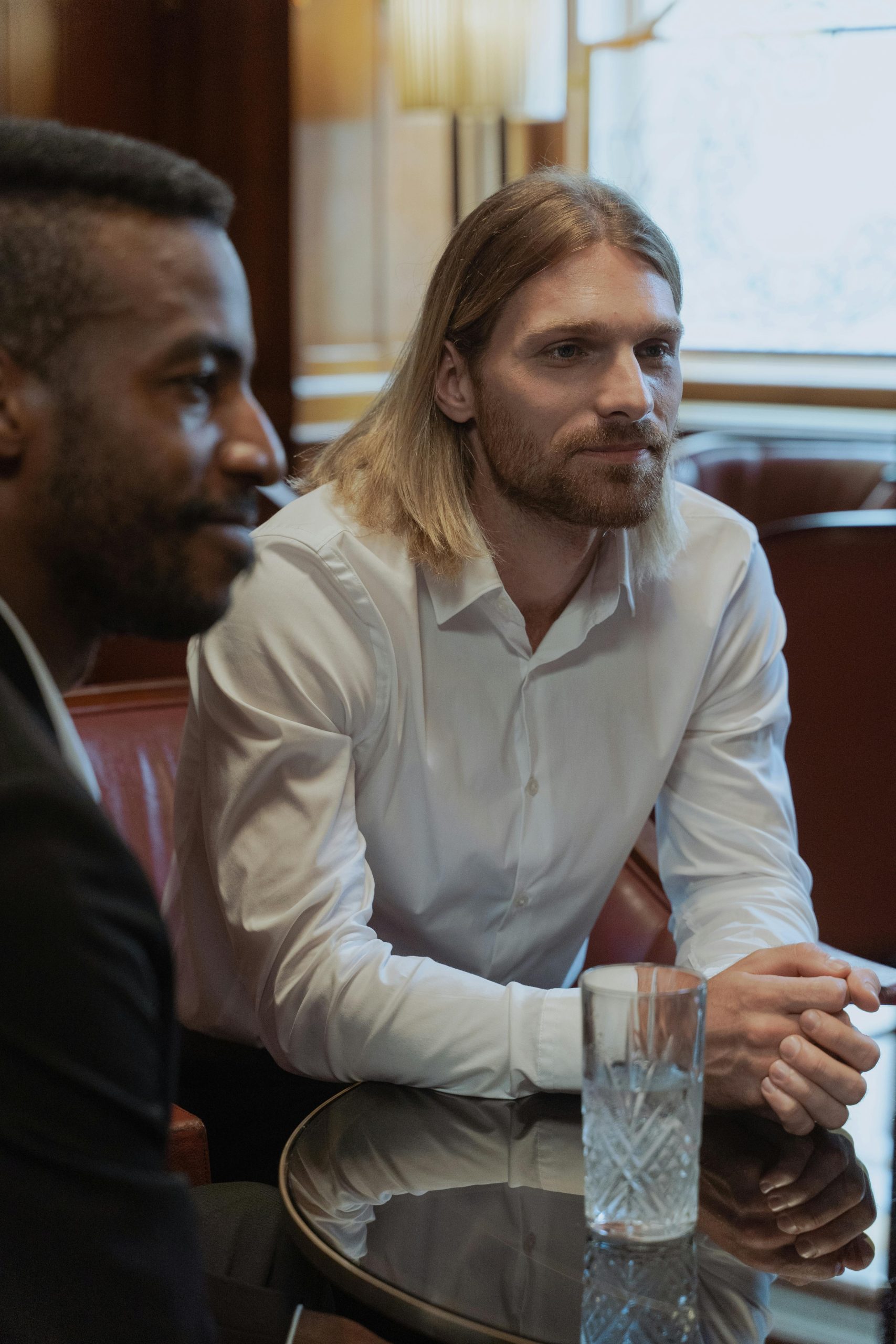 Two men in a formal setting engage in a business conversation at a restaurant.