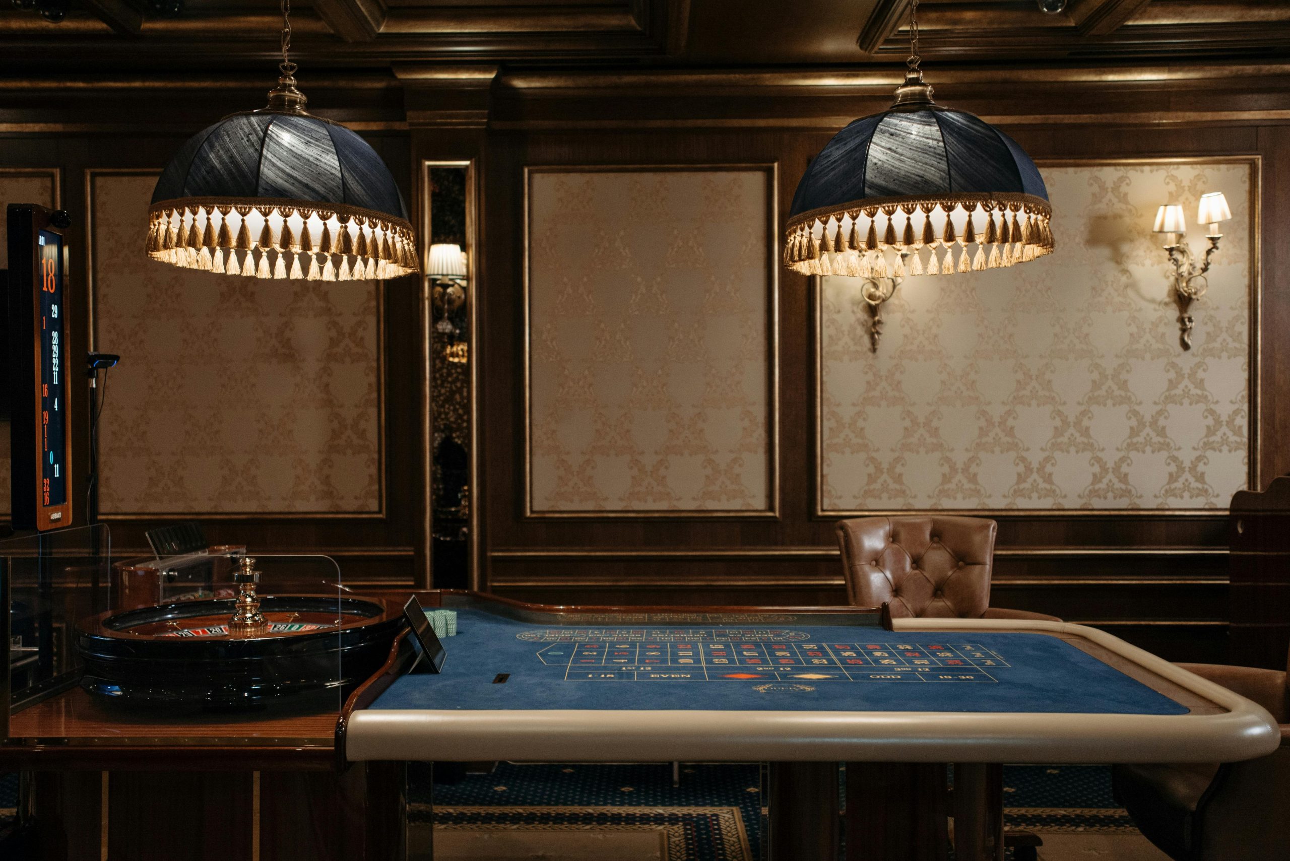 Luxurious casino interior featuring a traditional roulette table under stylish lamps.